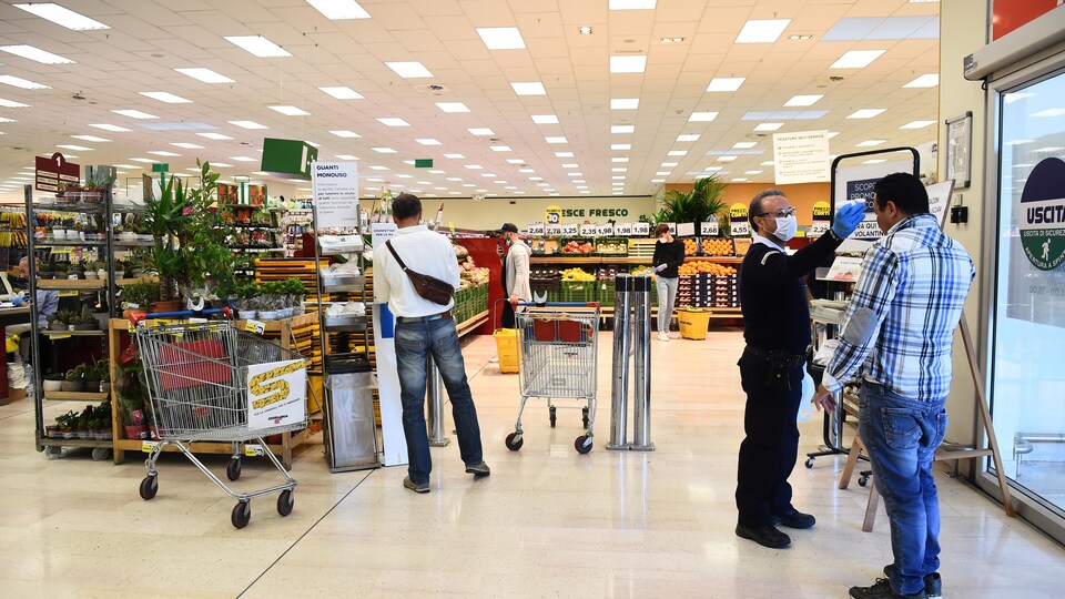 Un employé mesure la température d'un client dans un magasin.