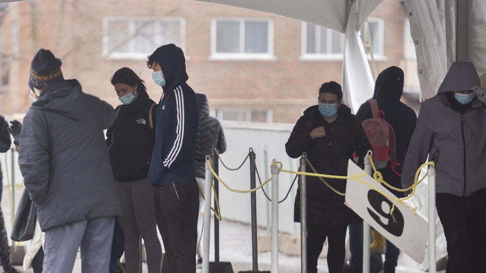 Des gens attendent en file à l'extérieur d'une clinique de vaccination, à Montréal.