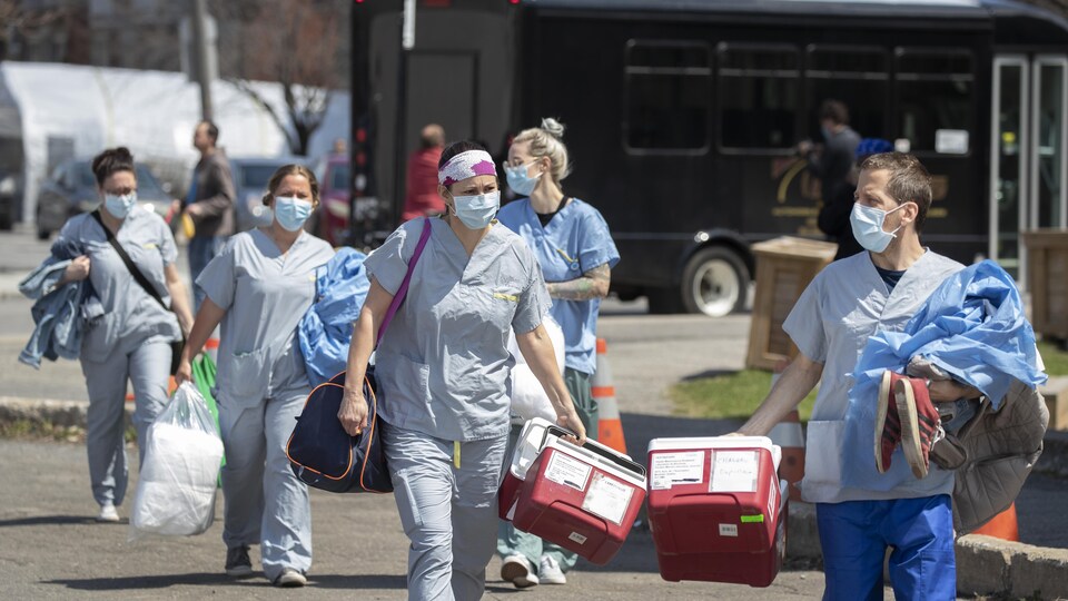 Des travailleurs de la santé masqués transportent du matériel médical.