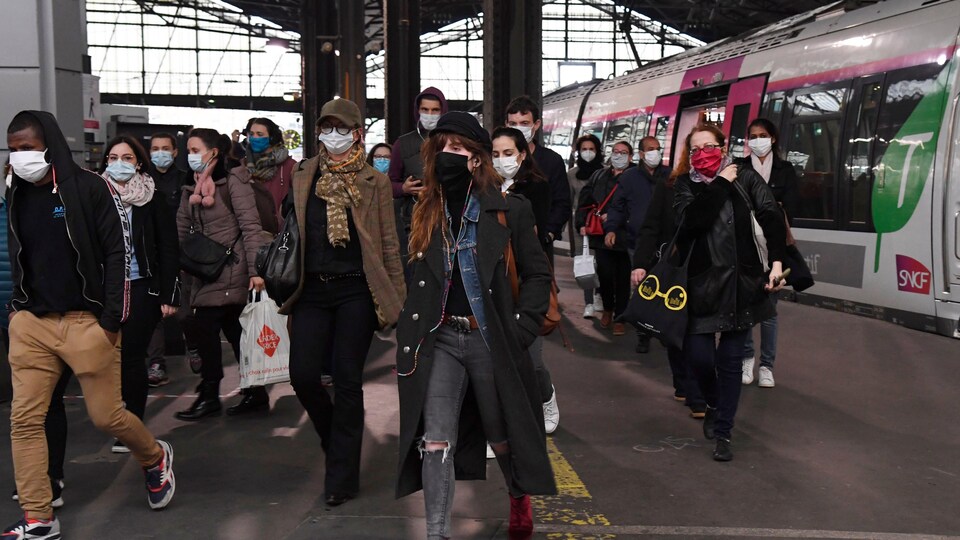 Des passagers débarquent d'un train à Paris en portant tous des masques médicaux.