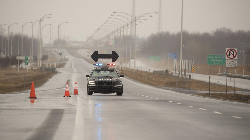 Une voiture de police dévie le trafic sur une route près d'un poste frontalier menant aux États-Unis.