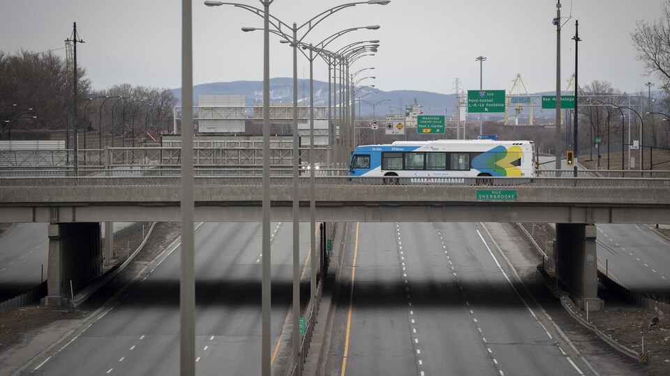 Un autobus roule sur un viaduc au-dessus d'une autoroute vide à Montréal.