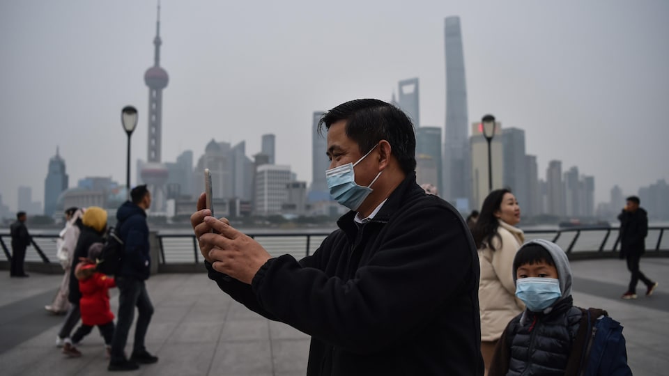 Un homme portant un masque respiratoire fait un égoportrait à Shanghai.