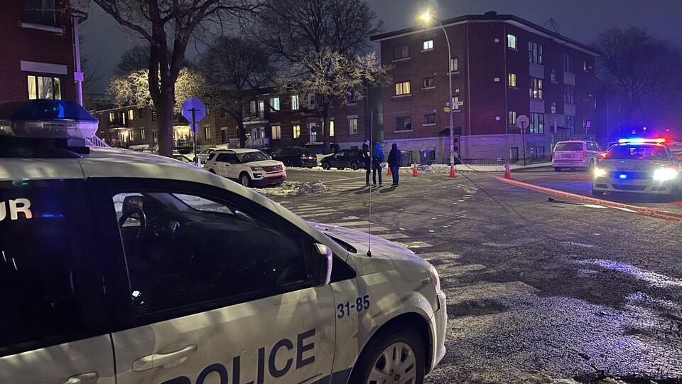 Des voitures de police bloquent la circulation devant un immeuble.