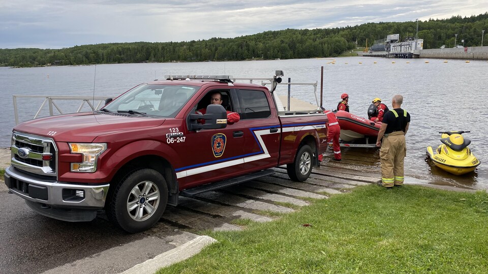 Une camionnette de pompiers sort un bateau pneumatique de l'eau.