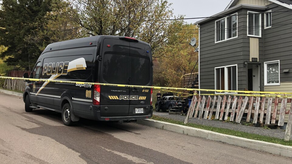 Un poste de commandement de la police et le véhicule incendié en arrière-plan.