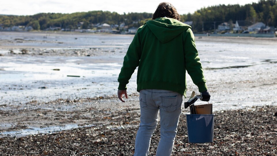 Une personne sur la plage ramasse des déchets.