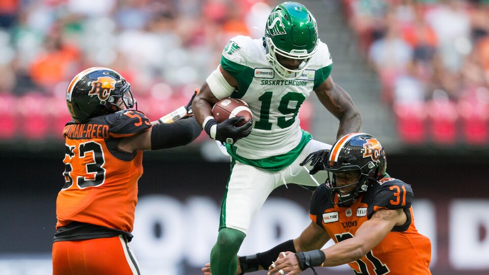 Cory Watson tente de se faufiler entre deux joueurs des Lions de la Colombie-Britannique.