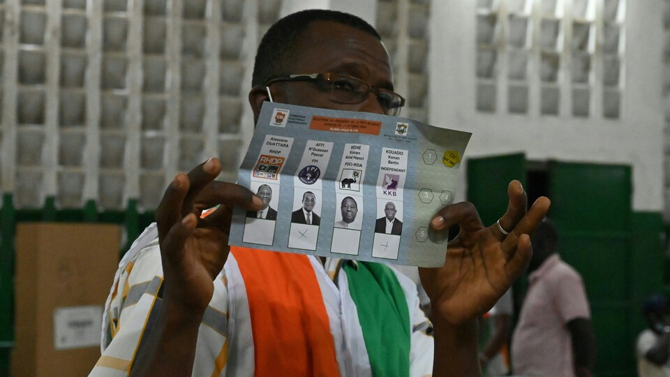 Un homme tient un bulletin de vote dans ses mains.