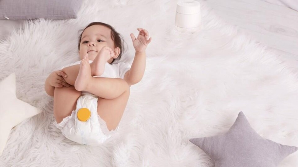 Un bébé porte une couche équipée d'un capteur Monit jaune. 