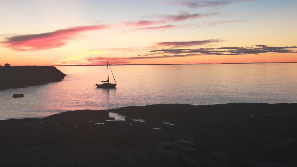 Un voilier est amarré à côté du quai de Pointe-au-Père, au crépuscule.