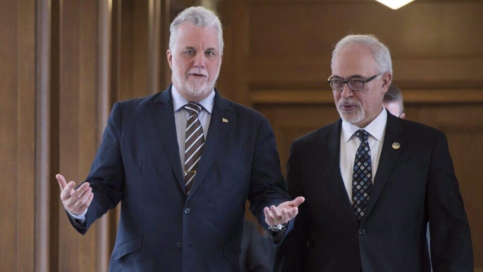 Carlos Leitao et Philippe Couillard marchant dans un corridor de l'Assemblée nationale.
