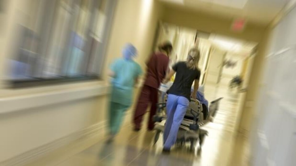 Trois infirmières marchent en poussant une civière.