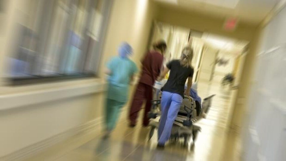 Des infirmières poussent une civière dans un couloir d'hôpital.