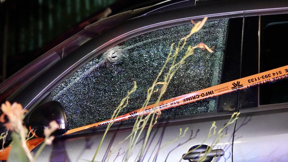 Un trou de balle dans la vitre d'une automobile sur le côté conducteur. Un ruban du SPVM délimite le périmètre.