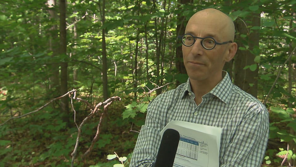 Daniel Desroches accorde une entrevue à Radio-Canada dans un boisé.