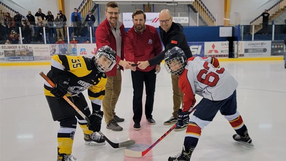 Deux jeunes joueurs de hockey face à face sur la glace, prêts pour la mise au jeu.