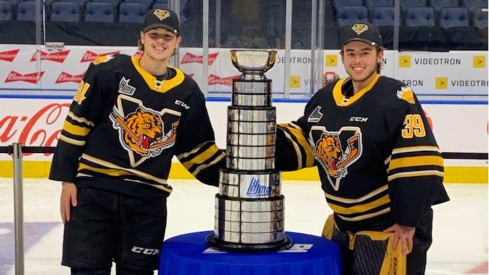 Zachaël Turgeon et Nathan Darveau ont chacun une main sur la Coupe du Président sur la glace du Centre Vidéotron de Québec.