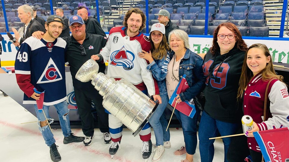 Un hockeyeur tient un trophée dans ses bras avec ses proches.