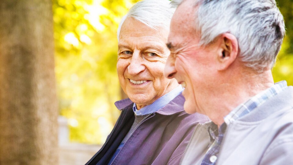 Deux hommes âgés assis sur un banc de parc.