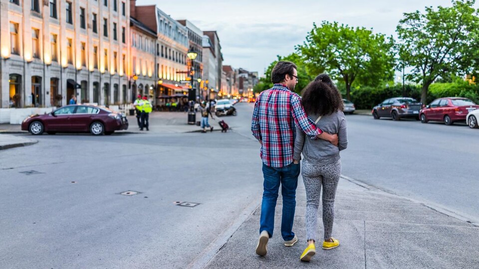Un couple marche en se tenant par la taille au milieu d'une rue.