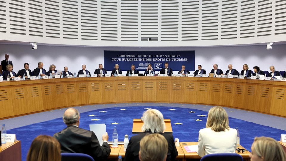 Les membres de la Cour européenne des droits de l'homme assis derrière leurs bureaux.