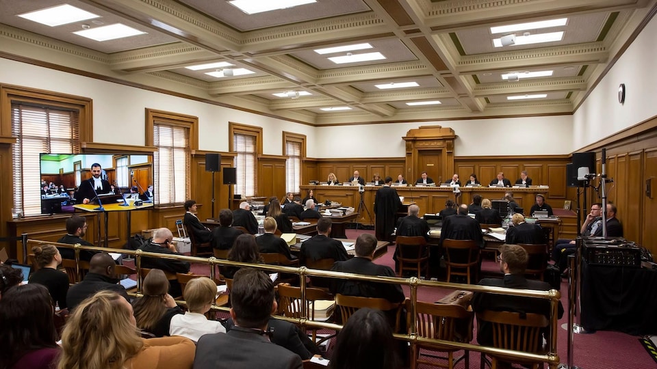Les 9 juges de la Cour suprême siègent au fond d'une salle d'audience remplie d'avocats et de membres du public.