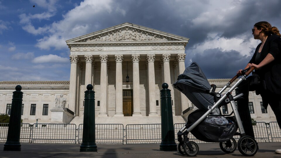 Une femme passe avec une poussette devant la Cour suprême.