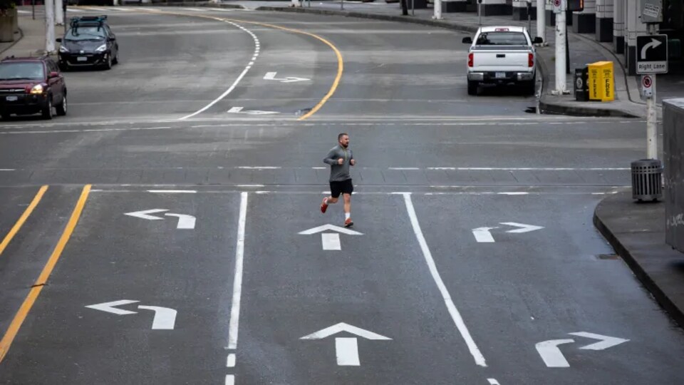 Un homme traverse une rue presque déserte.