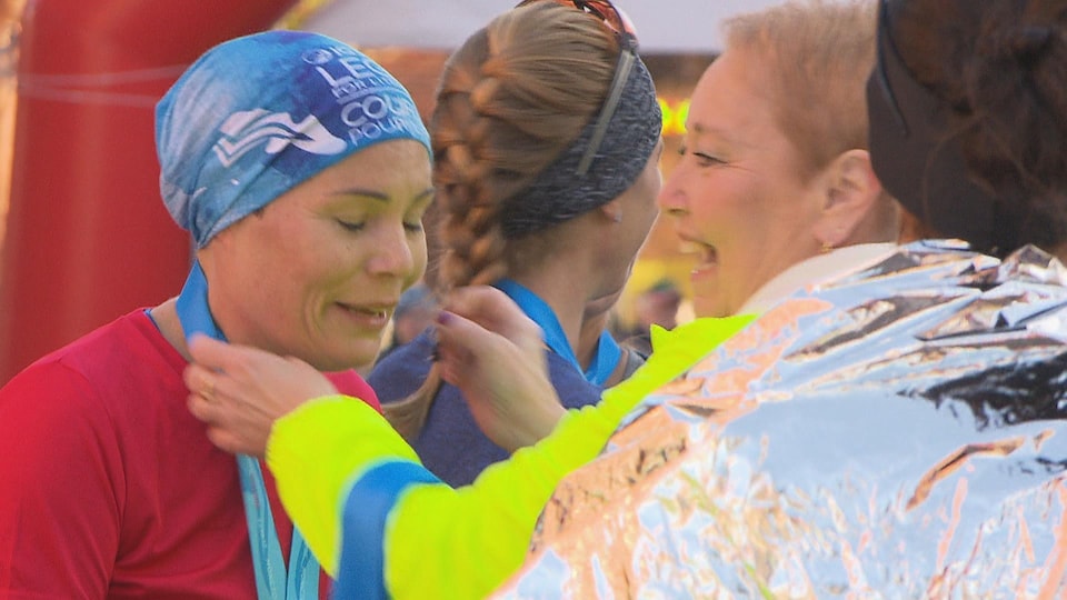 Une femme est heureuse de recevoir sa médaille après la course.