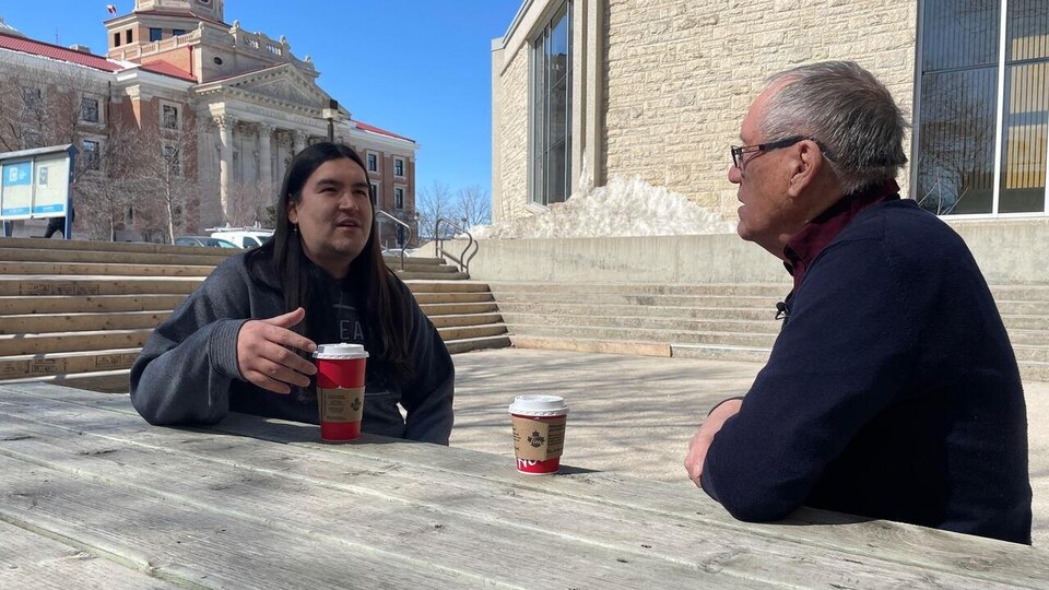 Ken Paupanekis et Samuel Robinson discutent en prenant un café.