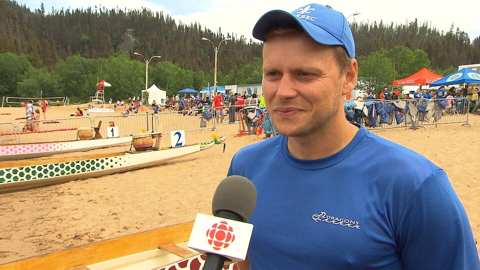 Il accorde une entrevue sur la plage près d'un bateau.