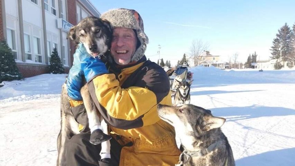 Un homme pose avec ses chiens, souriant.