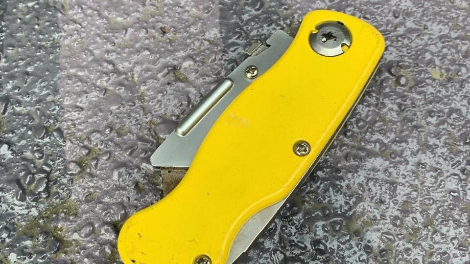 Un couteau rétractable jaune sur le trottoir.