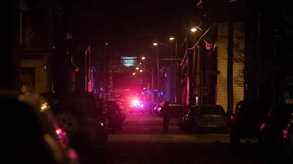 Une autopatrouille dans une rue avec les gyrophares allumés la nuit.