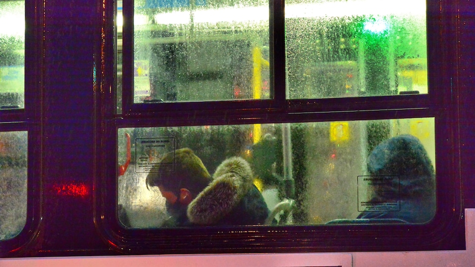 Un homme masqué assis dans un autobus.