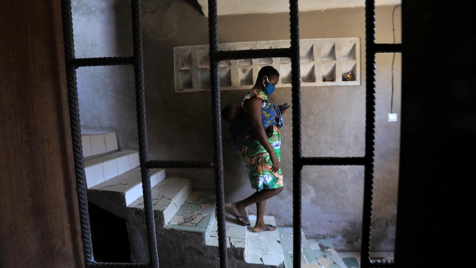 A woman wearing a COVID-19 protective mask walks down the stairs of a building in Abidjan, Côte d'Ivoire.