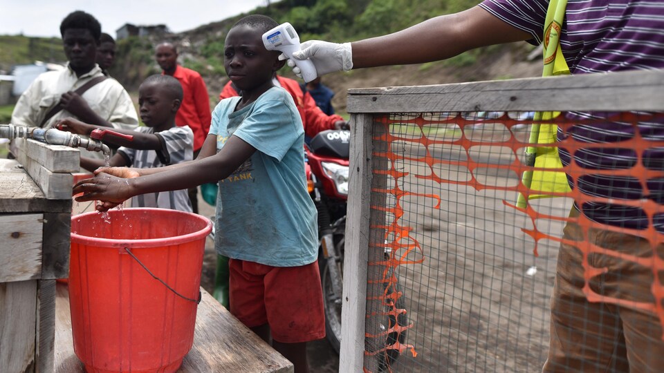 Un agent de santé vérifie la température d'un enfant congolais qui se lave les mains à Goma.