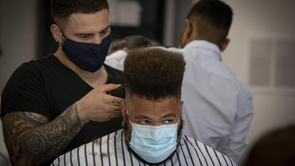 Un homme se fait raser les cheveux par un barbier.