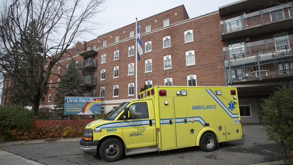 Une ambulance passe devant le CHSLD et une pancarte sur laquelle on peut lire : « Ça va bien aller ».