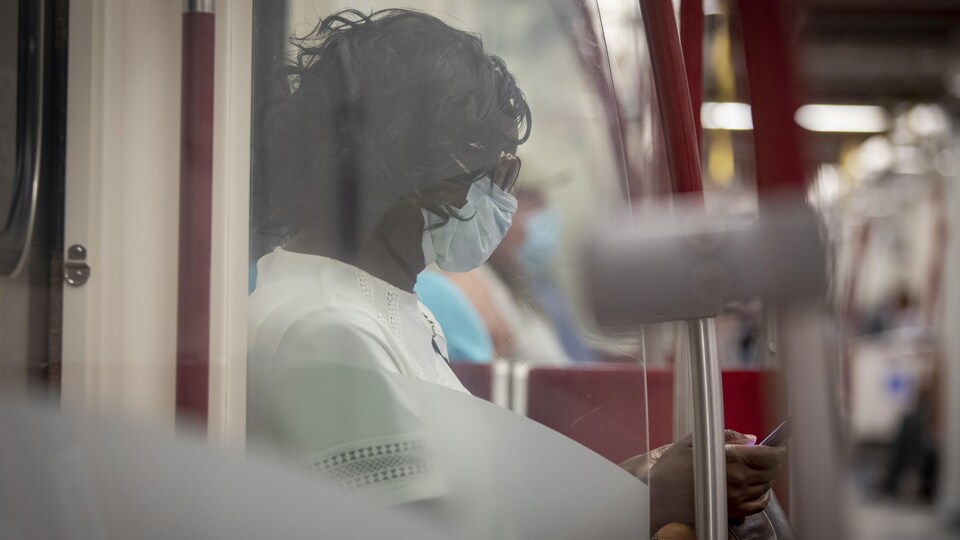 Une femme qui porte un masque consulte son téléphone.