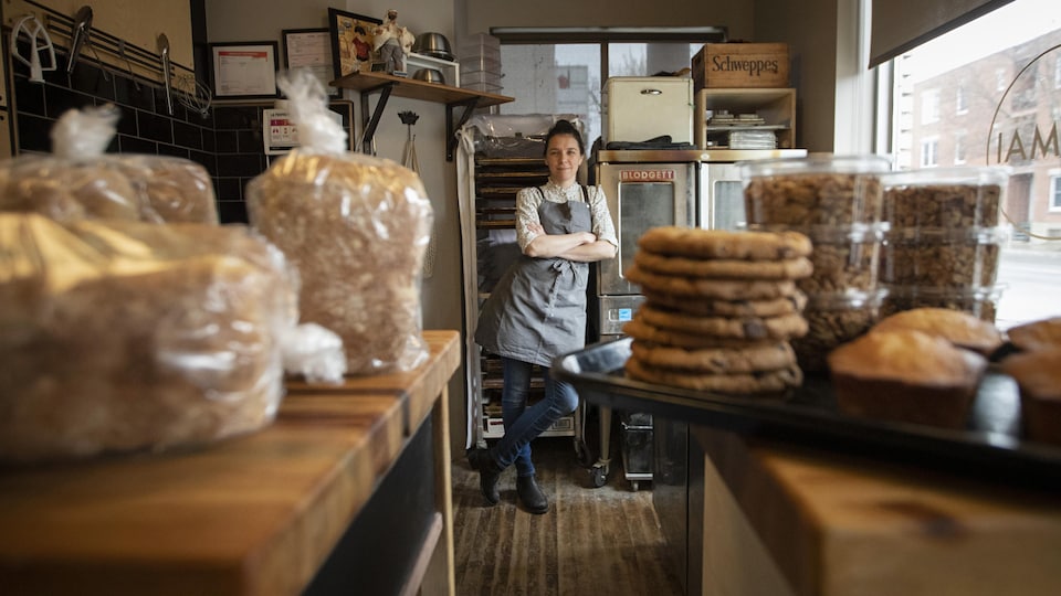 La boulangère dans son local de production, entourée de pains et de biscuits.