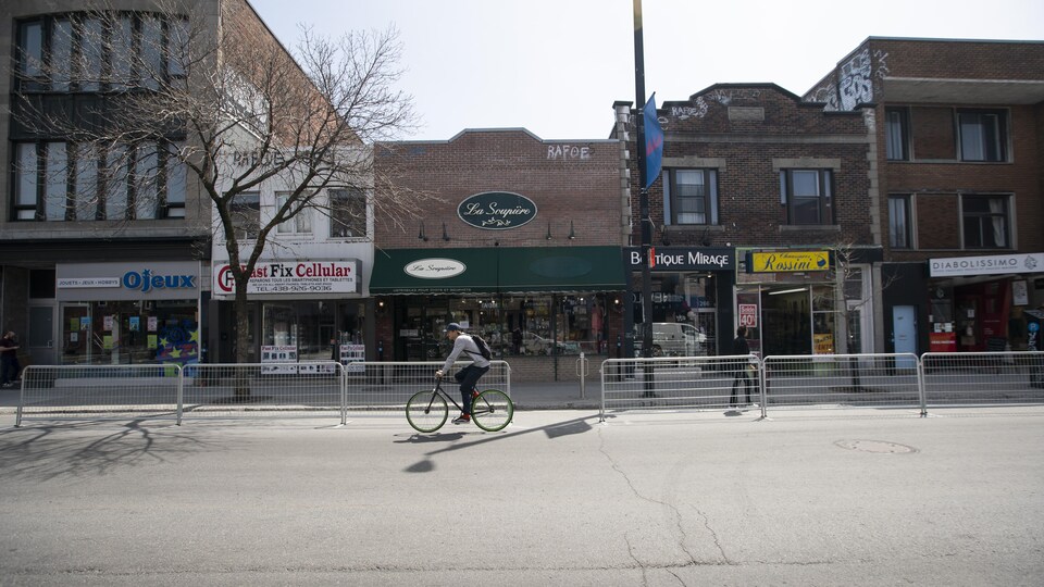 Un homme à vélo dans une rue commerciale presque déserte.