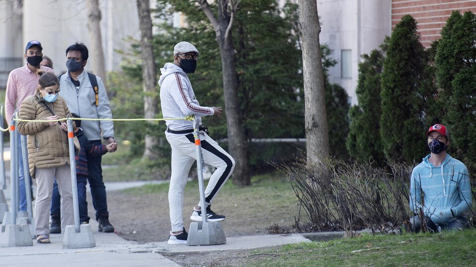 Les gens attendent en ligne, un jeune homme est à genoux par terre.