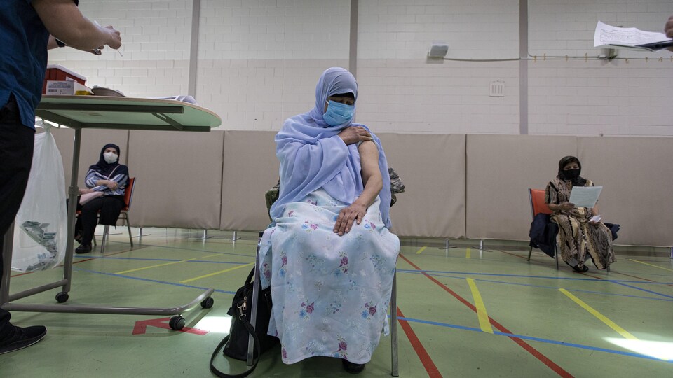 Une femme se prépare à recevoir son vaccin à une session de vaccination organisée à un centre communautaire de la communauté musulmane.