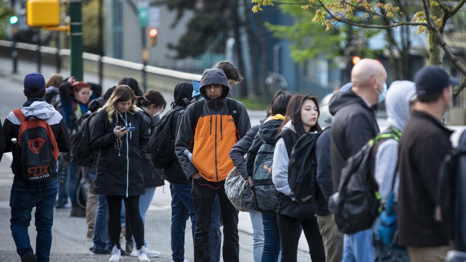 Des utilisateurs du transport en commun font la file à Vancouver. 