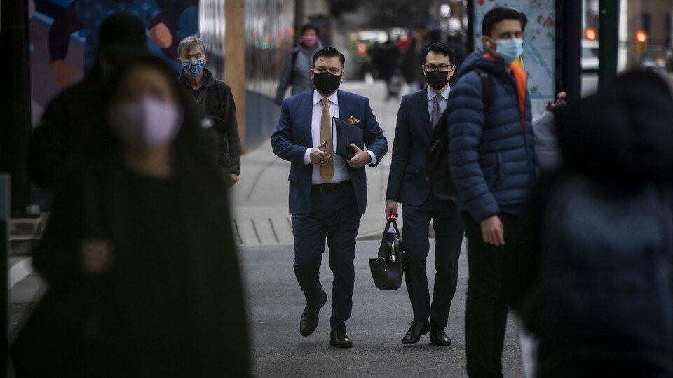 Des personnes dans la rue portant un masque.