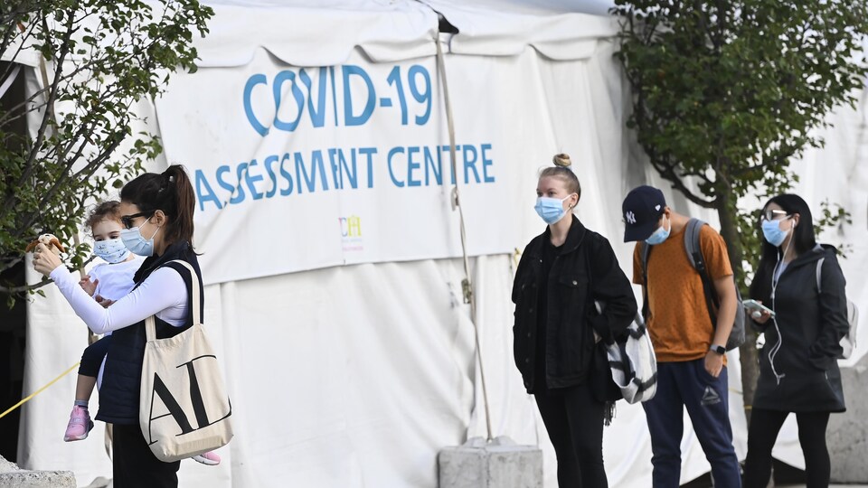 Des gens attendent en file à un centre de dépistage à Toronto.