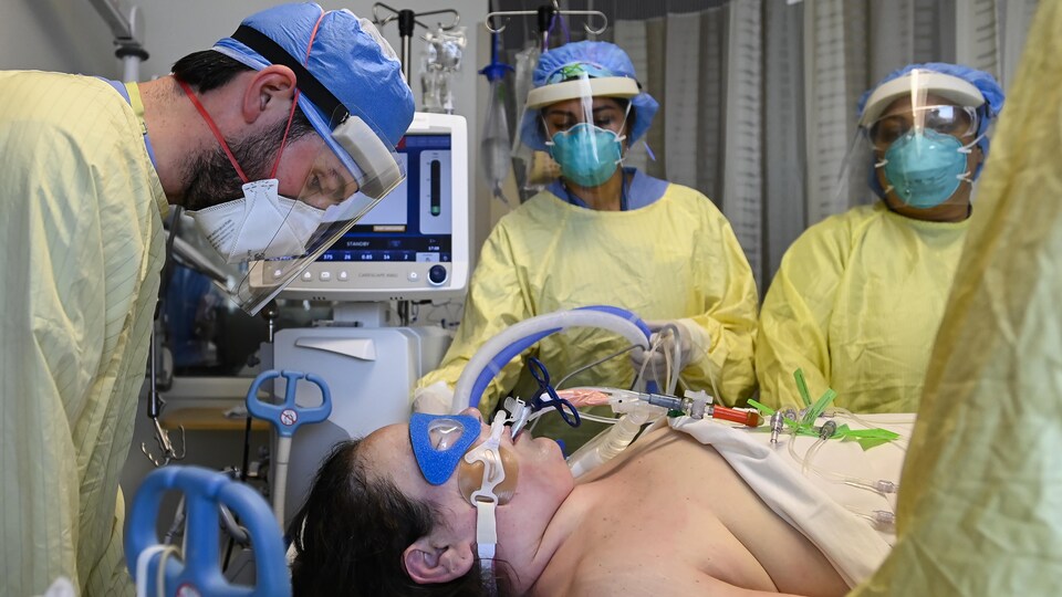 Une femme intubée entourée de personnel médical.
