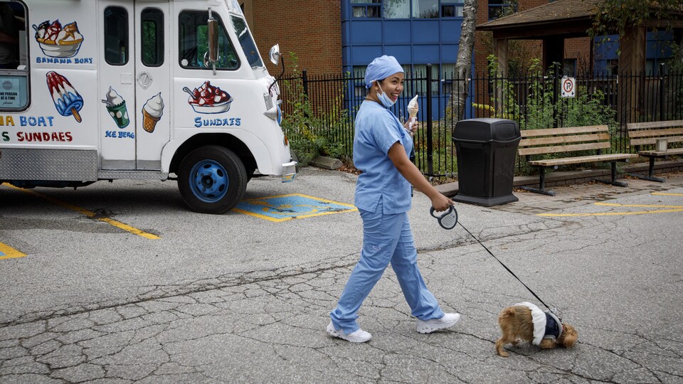 Une préposée du foyer Tony Stacey Centre For Veterans Care, à Scarborough fait marcher un chien et mange une crème glacée.